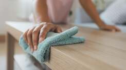 Person dusting a coffee table with a soft dust cloth