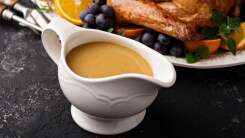 Gravy in a gravy boat next to a platter.