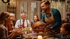A man serving the Thanksgiving turkey to his awaiting family.