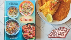 Chaat cookbook on a table next to an omelette with red sauce.