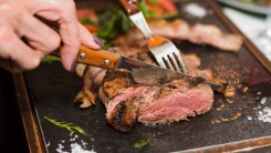 Woman's hands cutting steak with a steak knife.