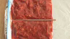 A bag of tomato sauce with a chopstick in the middle.