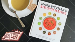 A bowl of soup next to Mark Bittman's Kitchen Matrix cookbook.