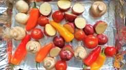 Assorted roasted vegetables on a foil-lined pan.