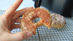 A hand holding an air-fried glazed doughnut.