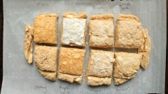 Eight biscuits on a baking pan with different coatings on top.