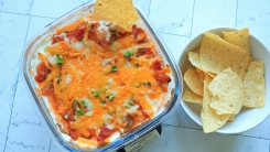 Seven layer dip in a Ninja Crispi container next to tortilla chips.