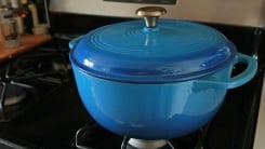 A blue Dutch oven on a stove top.