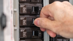man turning off electrical circuit breaker