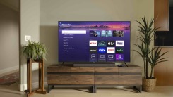 A TV in a living room connected to a Roku device. The TV has Roku's home screen on display.