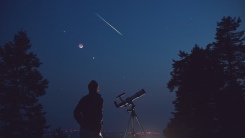 Man with telescope under night sky
