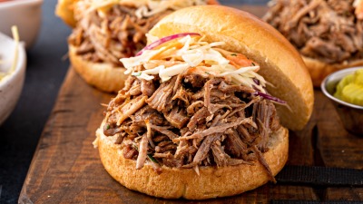 A pulled pork sandwich on a cuttingboard close up.