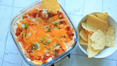 Seven layer dip in a Ninja Crispi container next to tortilla chips.