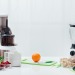 A juicer and a blender on a counter with fruits and veggies