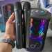 My hand holding the Soundcore Rave 3S microphones in my office with the Soundcore Rave 3S speaker in the back.