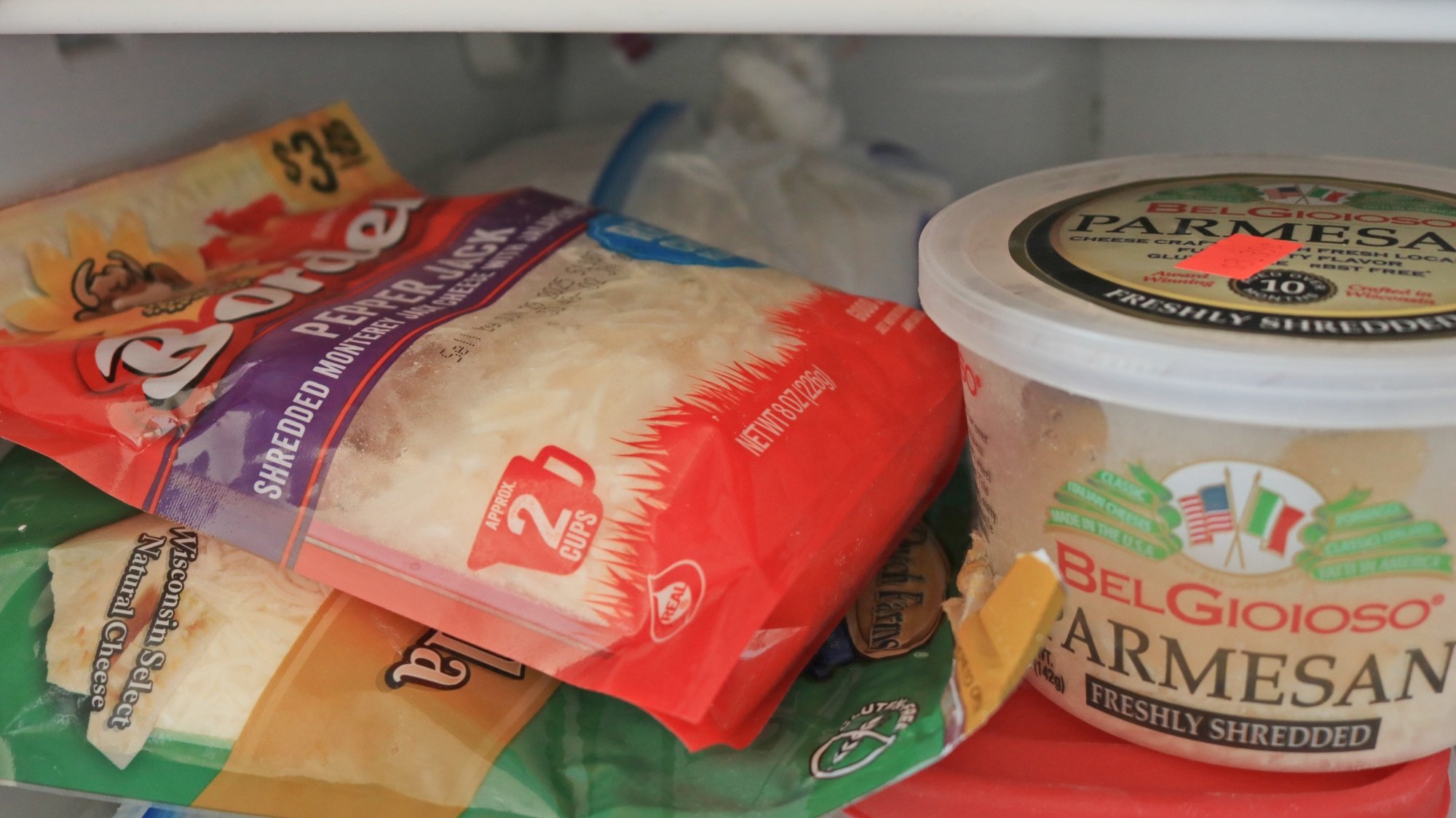 Bags of shredded cheese and a tub of parmesan in the freezer.