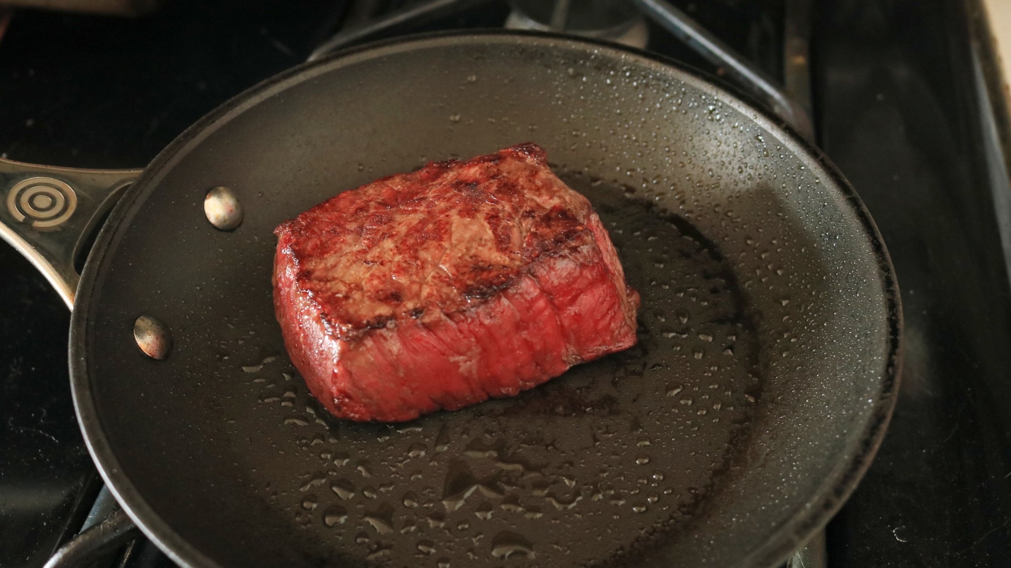 A steak searing in a frying pan.