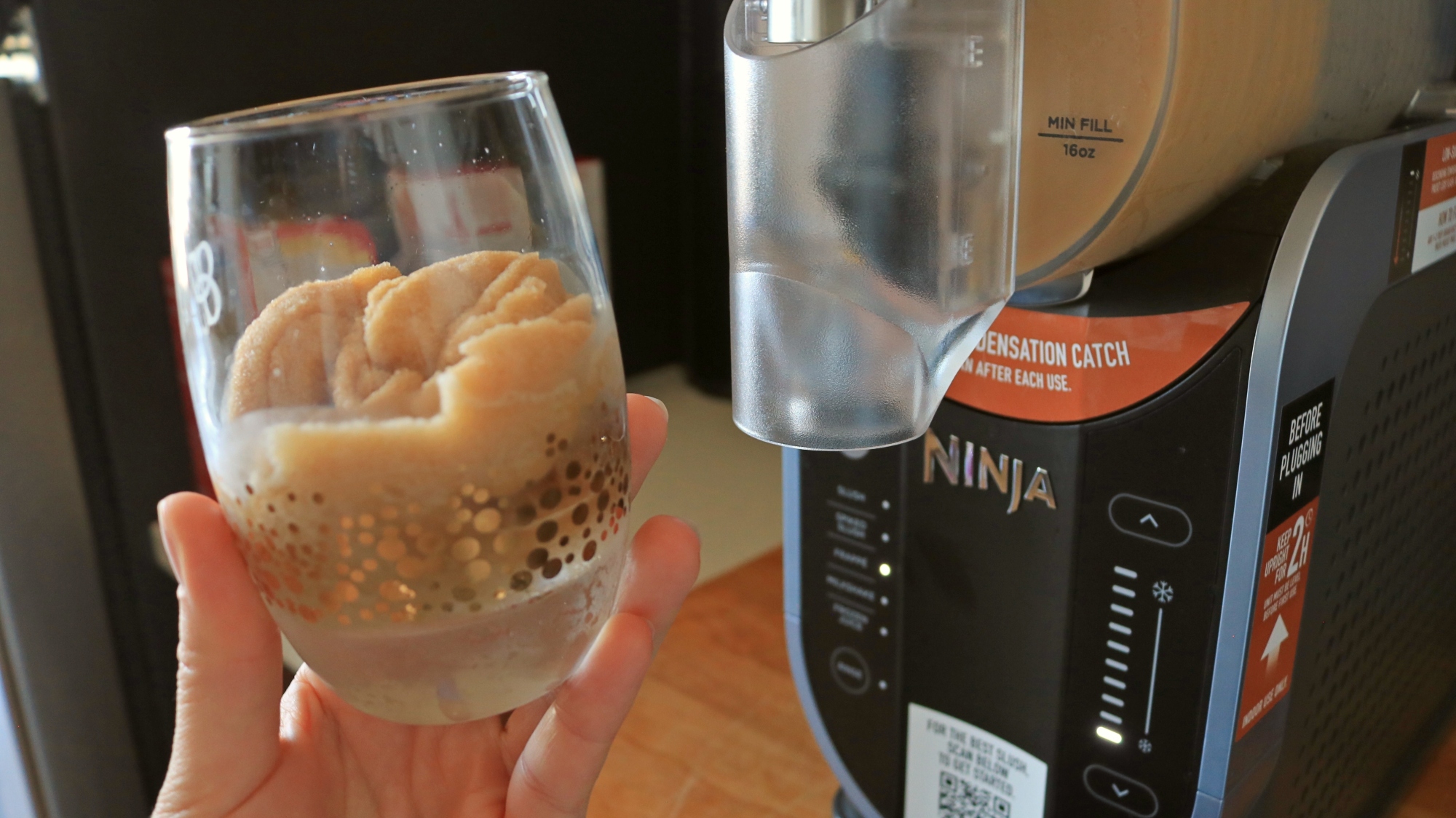 A cup of frappé coffee in front of the Ninja Slushi.