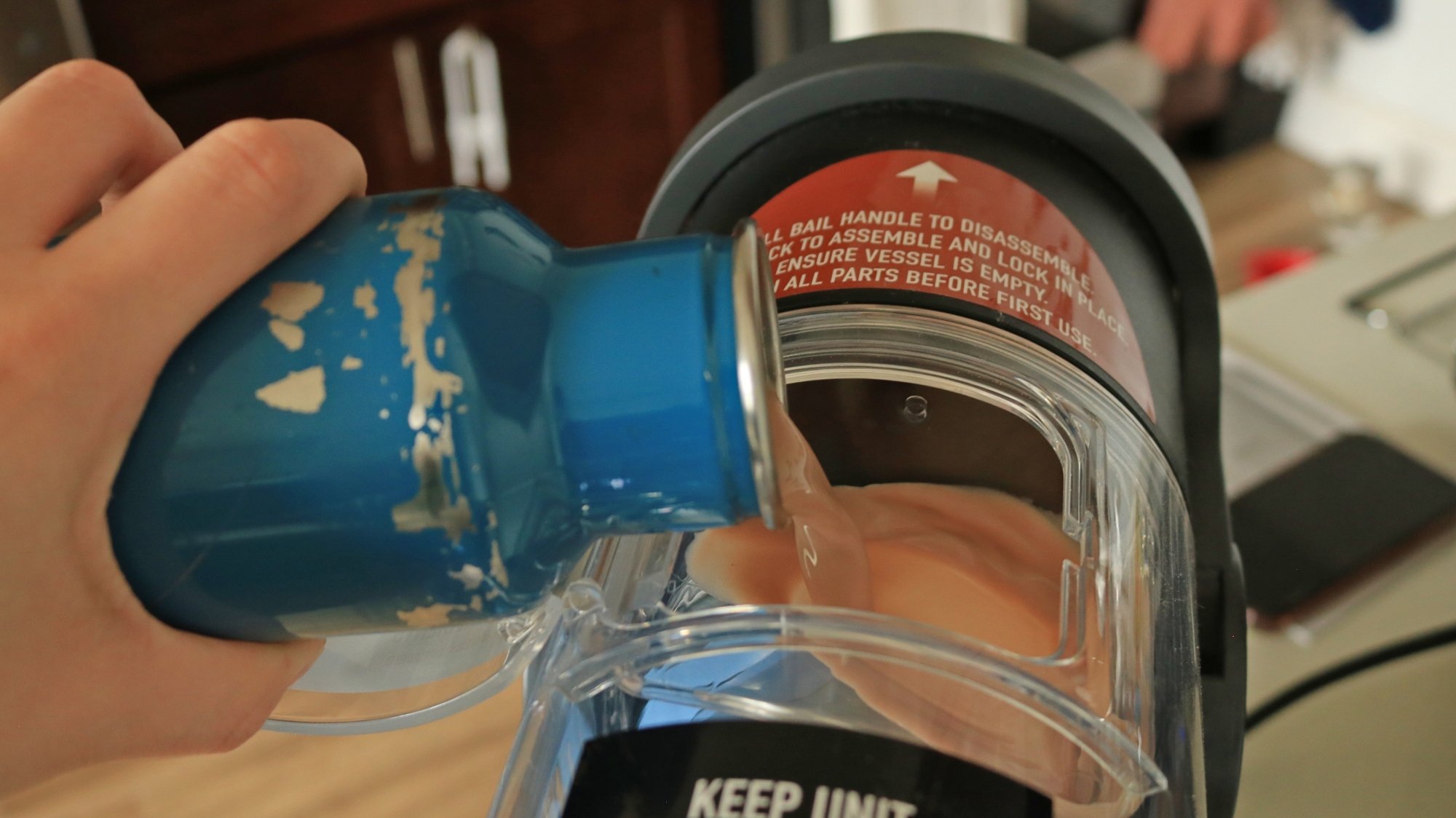 A person pouring a chocolate mixture into the Ninja Slushi vessel.