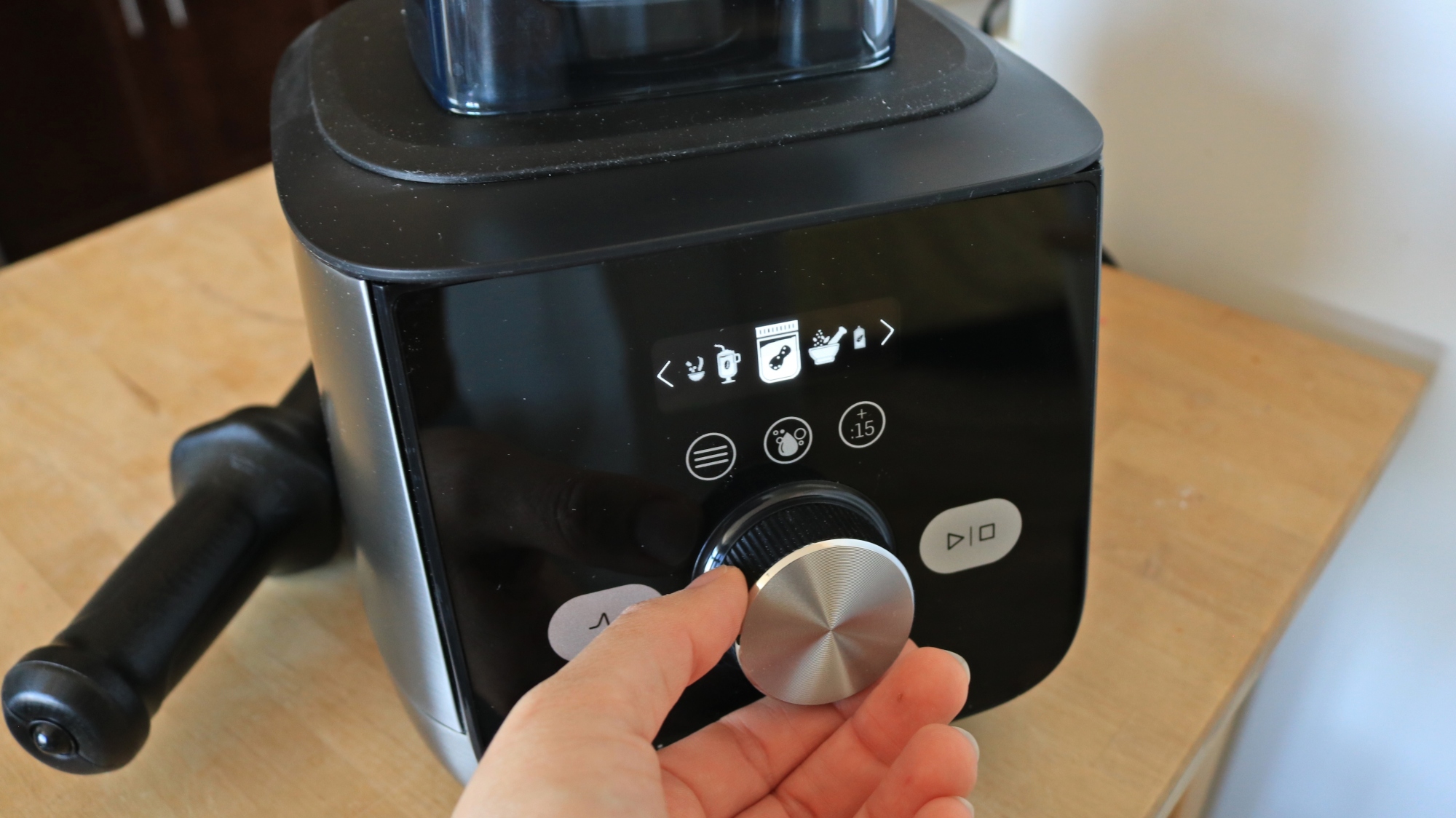 Hand selecting a setting on the Vitamix blender.