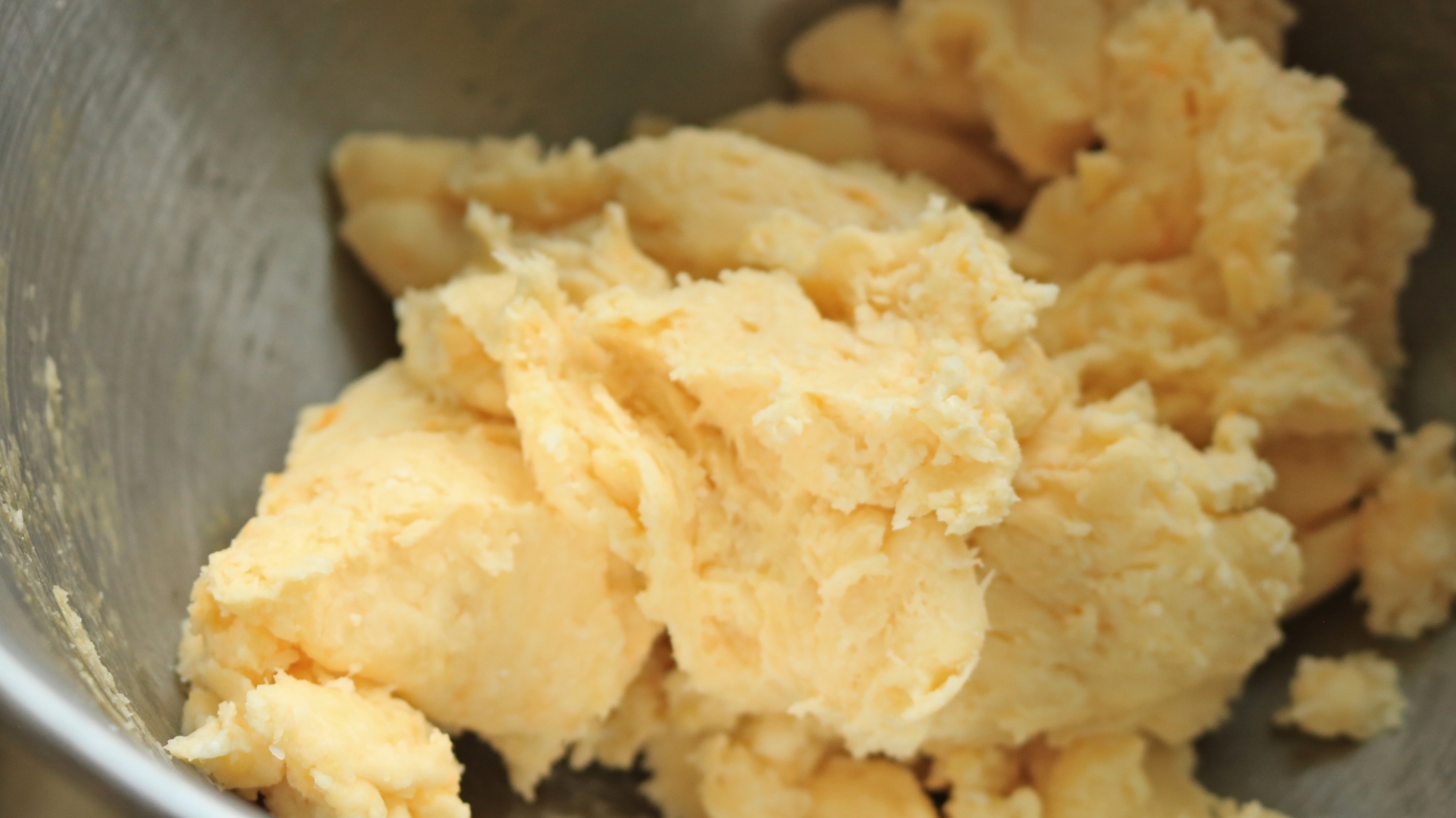 A light bread dough in a stand mixer bowl.