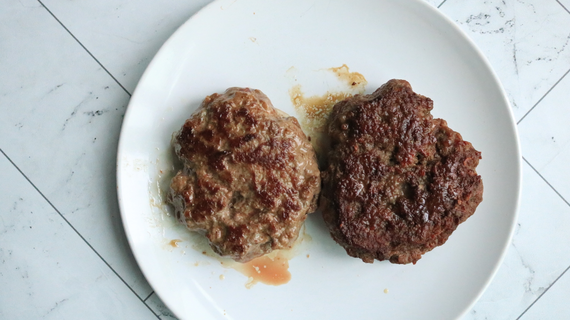 Two burger patties next to each other on a plate.