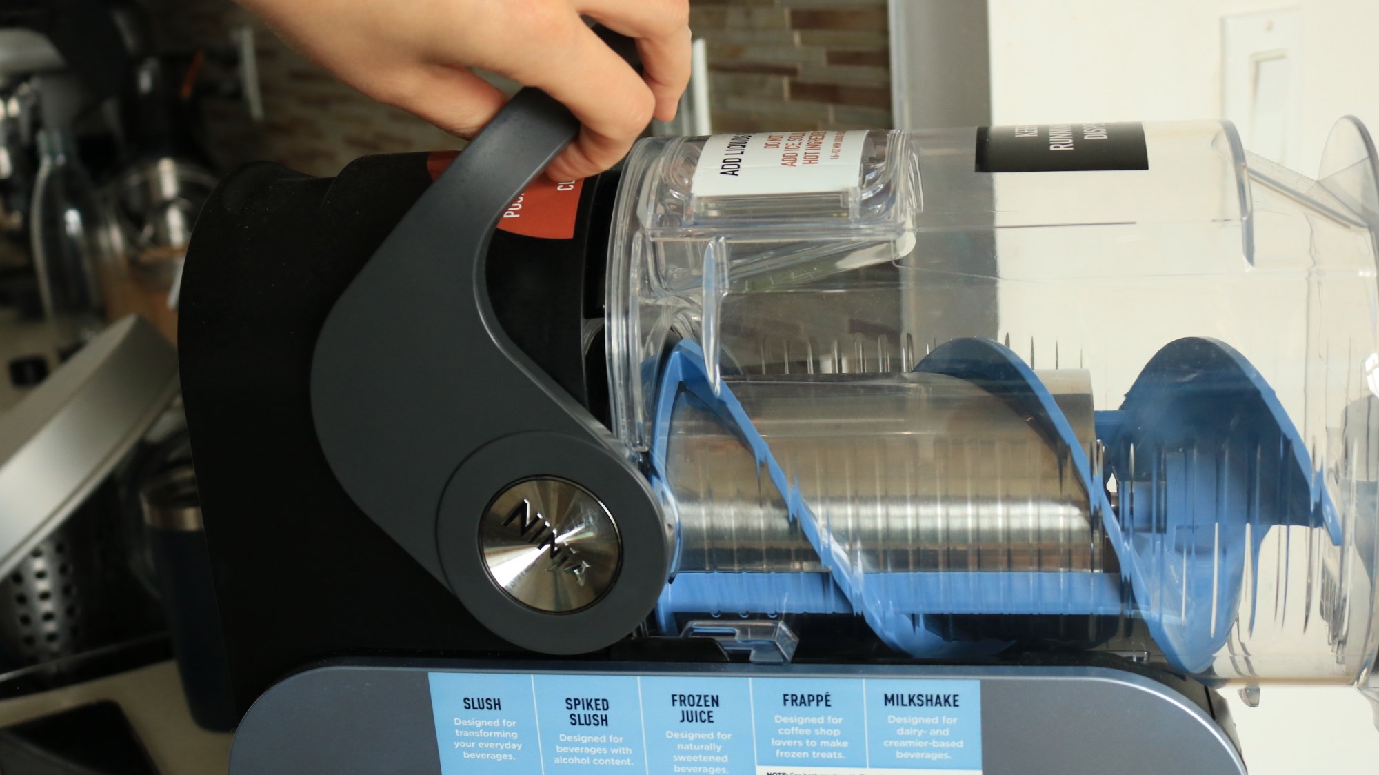 A person pulling the handle to secure the container on the Ninja Slushi.