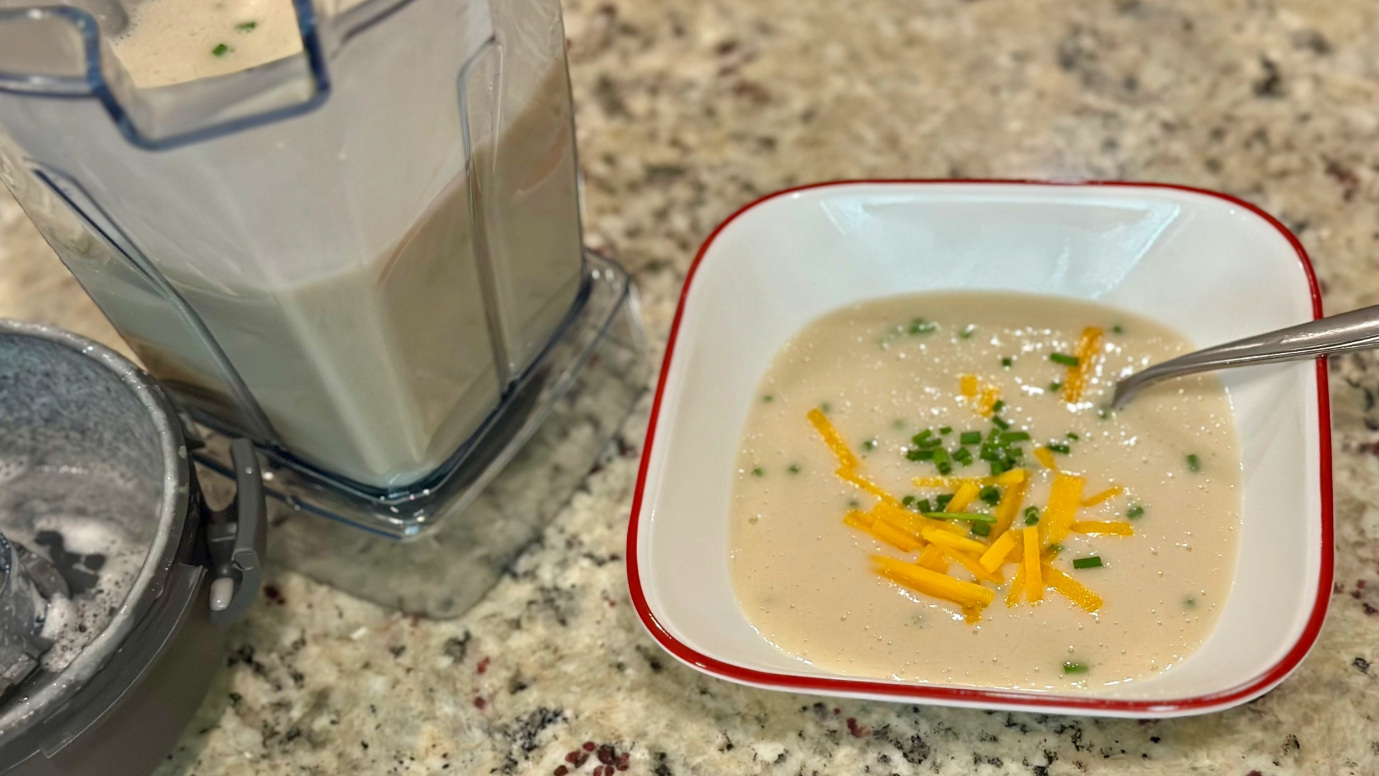 A bowl of potato cheddar soup next to the E310 blender.
