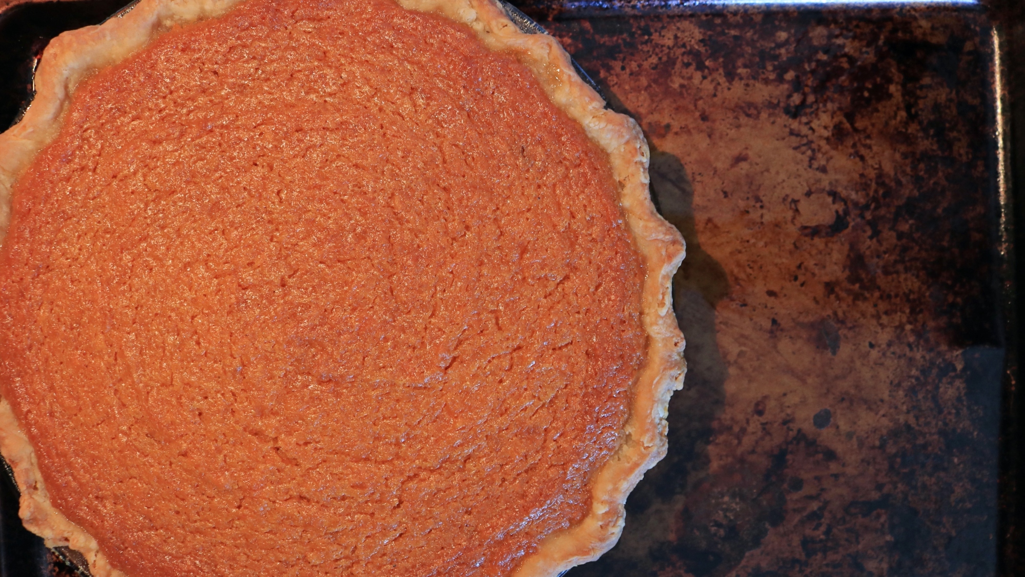 A sweet potato pie on a baking sheet.