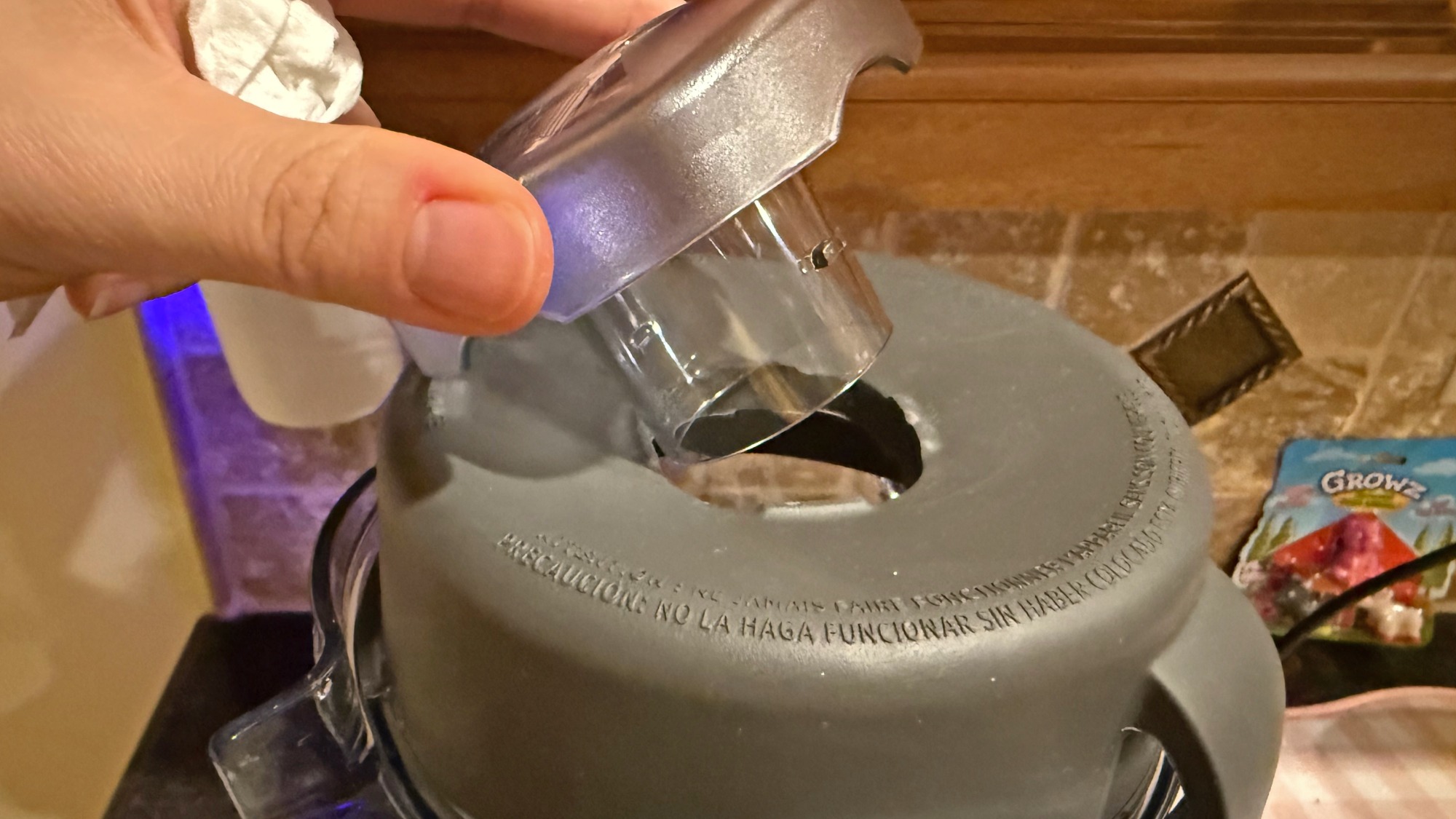 Hand removing the cap in the Vitamix's rubber lid.