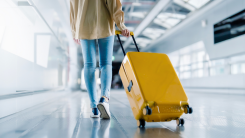 A woman in an airport walking with her suitcase