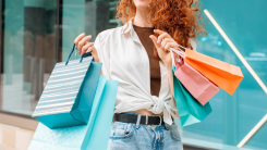 Woman with red curly hair holding shopping bags.