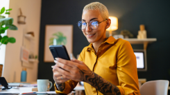Young woman using phone while working at her home office - stock photo