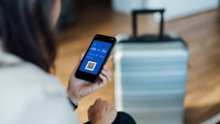 A person looks at a boarding pass on their phone next to luggage