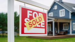 Sold sign in a yard in front of a house