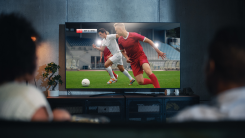 Couple on a couch watching sports on a large TV screen
