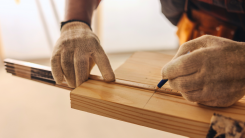 Carpenter measuring and cutting a wood plank
