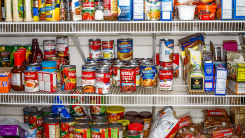 Shelves of a pantry filled with canned goods and bags of nuts