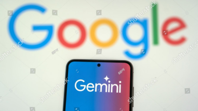 A photo of the google gemini logo on a smartphone with a large google logo visible in the background, letters on a white background. The image is covered in photo watermarks from Shutterstock