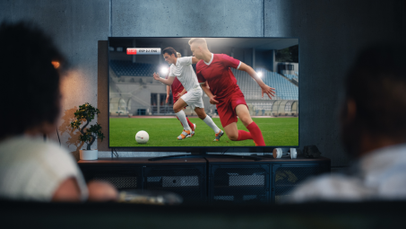 Couple on a couch watching sports on a large TV screen