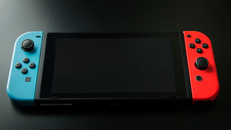 A Nintendo Switch with blue and red controllers, on a table displaying a black screen