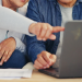 Couple on laptop pointing at screen,