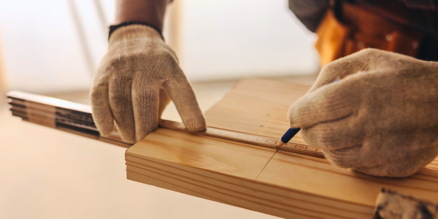 Carpenter measuring and cutting a wood plank