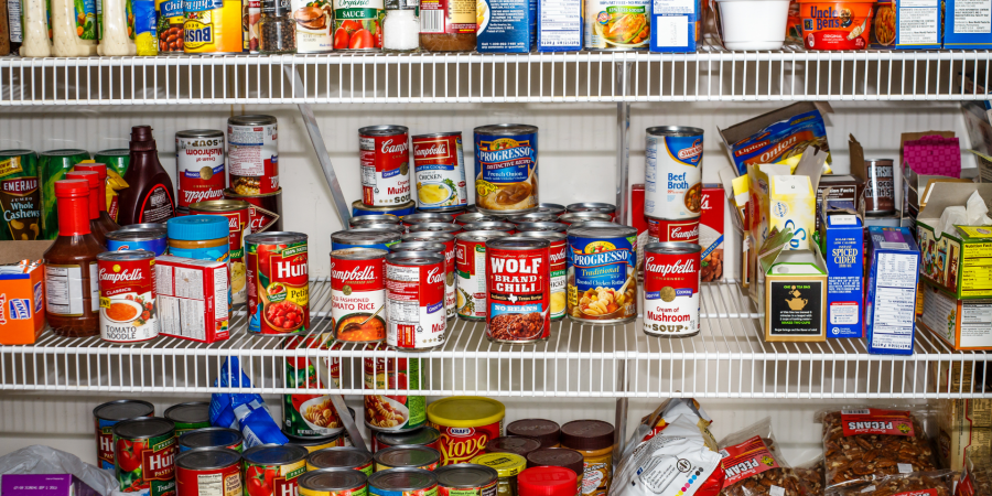 Shelves of a pantry filled with canned goods and bags of nuts