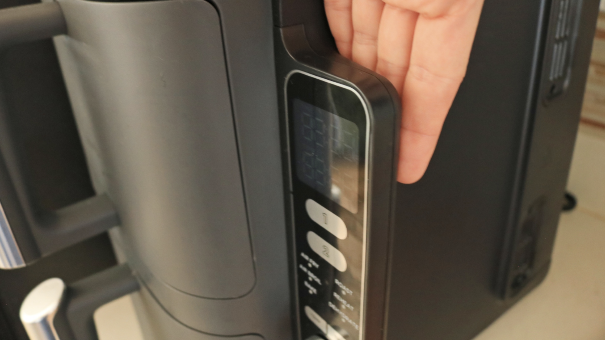 A hand behind the control panel of the Ninja DoubleStack to show scale.